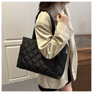 Detail of black quilted puffer tote bag with reinforced shoulder strap and side pocket