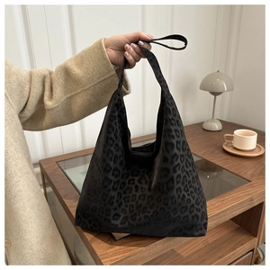 Detail view of large leopard print tote bag being carried in a stylish lifestyle setting