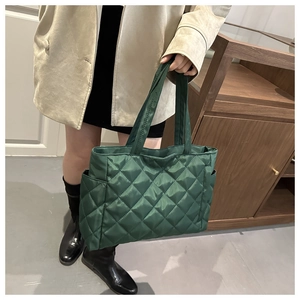 Detail of dark green quilted tote bag with side pocket and sleek diamond pattern