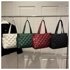 Detailed view of quilted tote bags in white, dark green, burgundy, and black colors