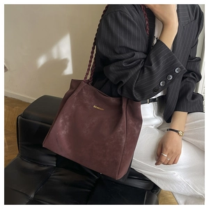 Detail of burgundy faux suede tote bag with woven shoulder strap and golden logo