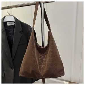 Detail showing the suede-like leopard print texture and wide strap of the hobo bag