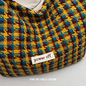 Detail van retro houndstooth geweven tas in geel en blauw met power off stoffen label