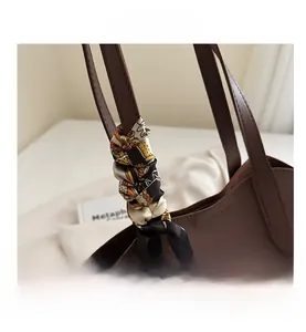 Detail eines braunen Leder-Shoppers mit modisch bedrucktem Seidentuch am Griff