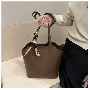 Detail einer dunkelbraunen Shopper-Tasche mit dekorativem Vintage-Schal am Griff