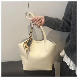 Detail einer großen cremefarbenen Shopper-Tasche mit elegantem Seidenschal am Griff