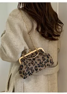 Detail of leopard print faux fur frame bag with gold chain strap on beige coat