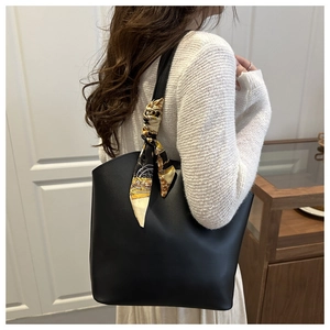 Schwarze Leder-Shopper-Tasche mit elegantem Seidenschal-Detail am Tragegriff im Fokus
