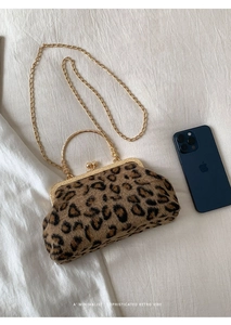 Macro detail of leopard print bag with gold clasp and chain strap next to smartphone