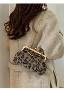 Detailed view of leopard print plush bag with gold metal frame and handle on a model