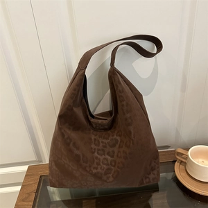 Brown leopard print oversized tote bag with minimalist hobo silhouette on wooden table
