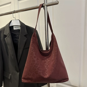 Burgundy leopard print hobo tote bag with wide strap hanging in a stylish setting