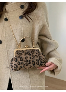 Detail of leopard print suede bag with gold frame and chain on a beige coat