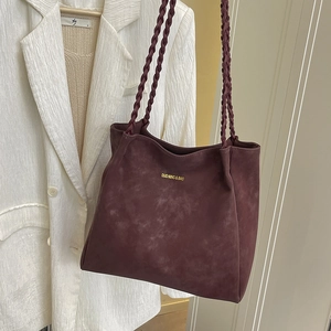 Vintage burgundy faux suede tote bag with woven straps on beige blazer display
