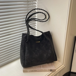 Retro black faux suede tote bag with woven handles on a white window sill