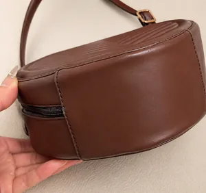 Close-up of precise stitching and quality PU leather on the dark brown crossbody bag