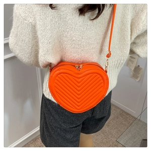 Detail of orange heart-shaped crossbody bag with V-quilted faux leather and gold zipper