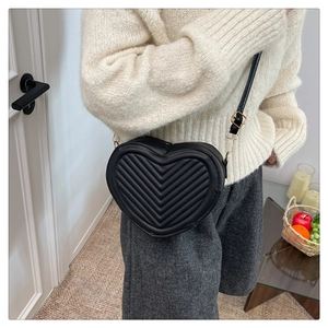Detail of black heart-shaped chevron quilted crossbody bag with gold-tone hardware detail