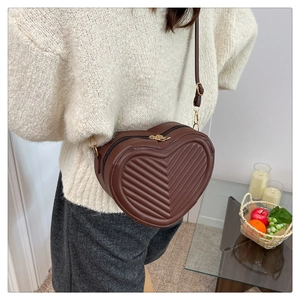 Detail of dark brown heart-shaped crossbody bag with V-quilted faux leather pattern