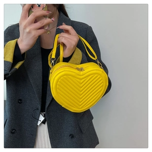 Detail of a bright yellow heart-shaped bag with chevron quilting and golden hardware