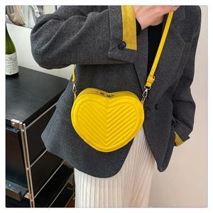 Bright yellow heart-shaped crossbody bag with V-quilted pattern and silver hardware detail