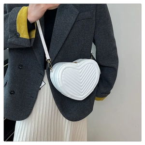 Close-up of a white heart-shaped crossbody bag featuring V-quilted faux leather pattern