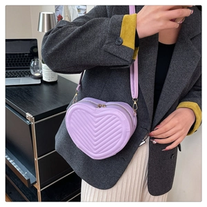 Detail of purple heart-shaped crossbody bag with quilted V-textures and gold zippers