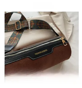 Close-up of brown matte cylinder bag featuring colorful ethnic style wide strap and hardware