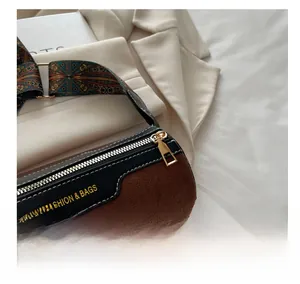 Detail of smooth gold zipper and matte brown texture on cylinder crossbody bag