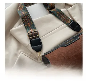 Close-up of brown cylinder bag with ethnic patterned wide strap and gold hardware