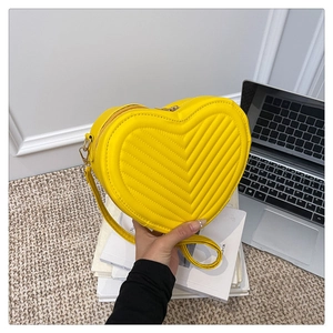 Detail of yellow heart-shaped quilted shoulder bag with golden zipper and strap