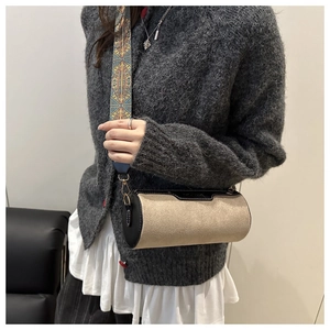Detail of canvas cylinder bag with black leather trim and vintage patterned wide strap