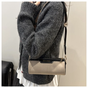 Close-up of beige cylindrical bag with wide vintage strap worn by model