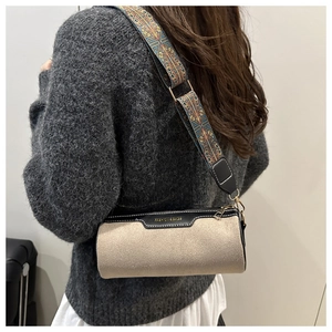 Close-up of beige suede cylinder bag with a wide ethnic style embroidered strap