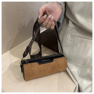 Detail view of the brown suede barrel bag with contrast trim and ethnic style wide strap
