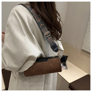 Detail view of cylinder bag with suede finish and colorful bohemian wide strap
