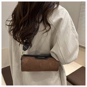 Detail of a brown suede cylinder bag featuring a vintage geometric wide strap and zipper