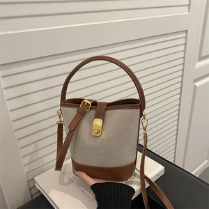 Chic cream canvas bucket bag with brown leather trim and golden twist lock closure