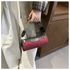 Detail of burgundy frosted cylinder bag with floral wide strap and gold fashion logo