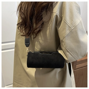 Detail of black cylinder bag with golden lettering and colorful ethnic style wide strap