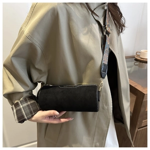 Detail of black cylinder bag with frosted texture and vintage bohemian shoulder strap