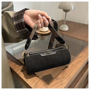 Detail of black suede cylinder bag with jacquard strap and fashion lettering