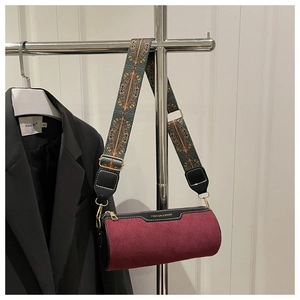 Detail of burgundy suede cylinder bag with a wide ethnic style jacquard shoulder strap