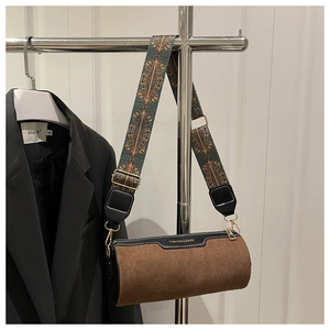 Detail of retro brown cylindrical bucket bag with ethnic patterned wide strap and gold zipper