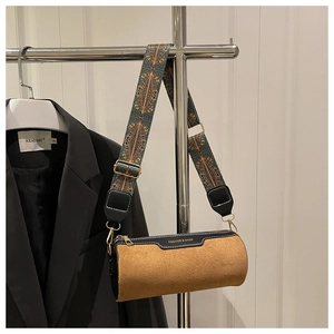 Detail of brown suede cylinder bag with ethnic strap and gold hardware finish