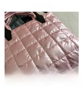 Detail of pink quilted tote bag with metallic sheen fabric and black handle base