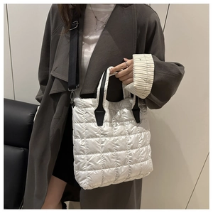 Detail of white quilted tote bag with metallic finish and adjustable black strap