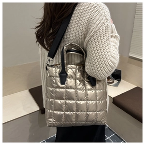 Detail of metallic gold quilted tote bag showing detachable black wide shoulder strap