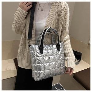 Detailed view of silver quilted tote bag with metallic finish and black fabric handles
