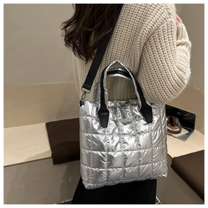 Detailed view of silver quilted tote bag with black strap worn by a model